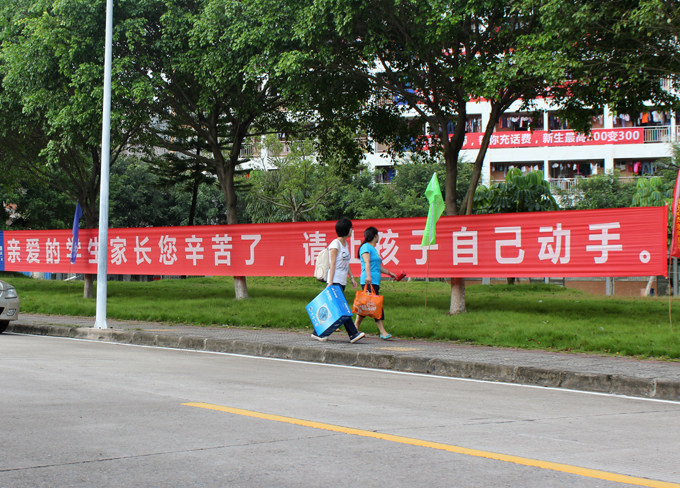 新生与家长正边走边看着路边的“另类标语”